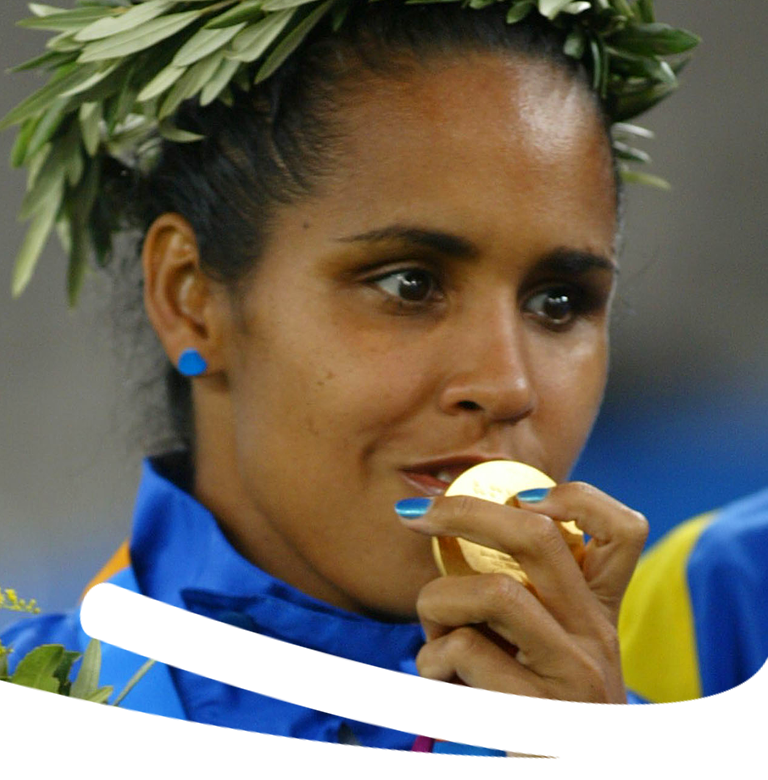 Foto do rosto de Adria com coroa de louros e uniforme azul beijando medalha.